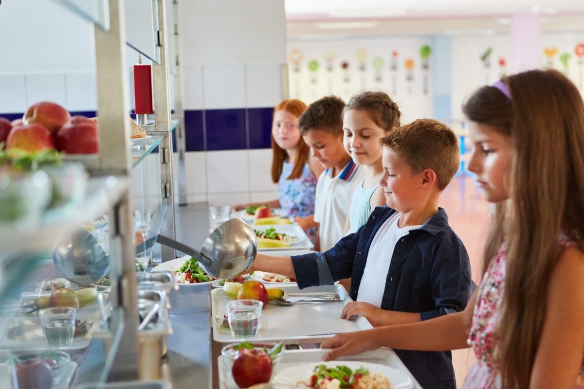 Elementary school students going through the school lunch line with trays