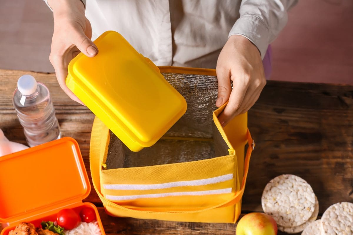 Parent packing lunchbox into school backpack