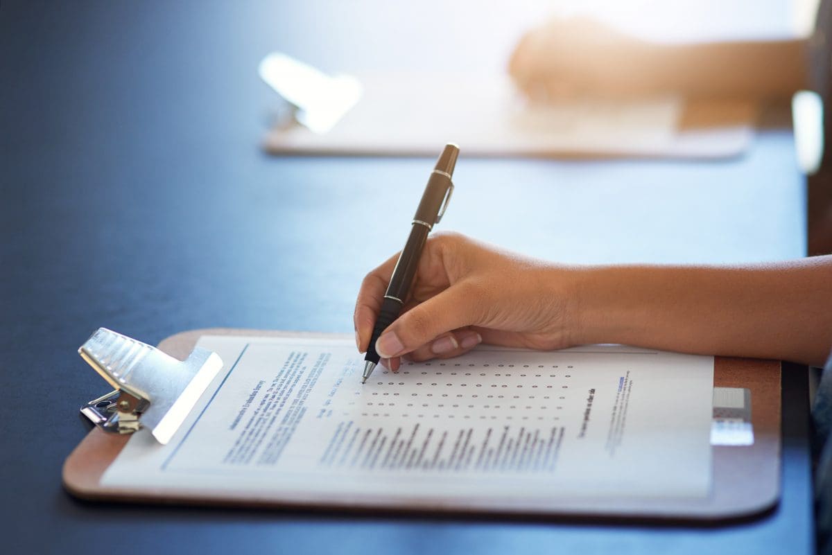 Hands holding pens and writing on clipboards