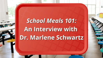 A red school lunch tray in a cafeteria. The words "School Meals 101: An Interview with Dr. Marlene Schwartz" are displayed.